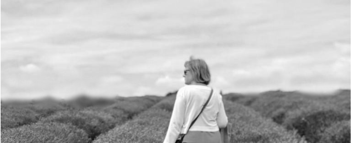 An older lady walking through fields.